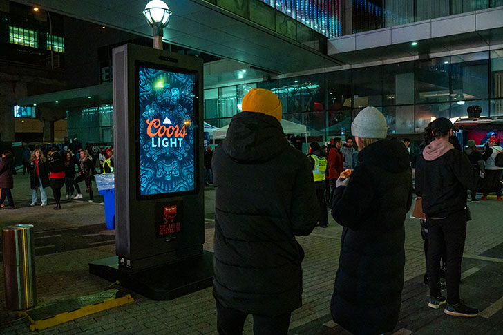 People standing next to an outdoor advertising sign